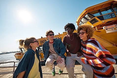 Four people wearing sunglasses in front of a harbour ferry in Hamburg