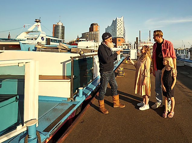 Tourguide spricht mit Familie vor Barkasse im Hamburger Hafen