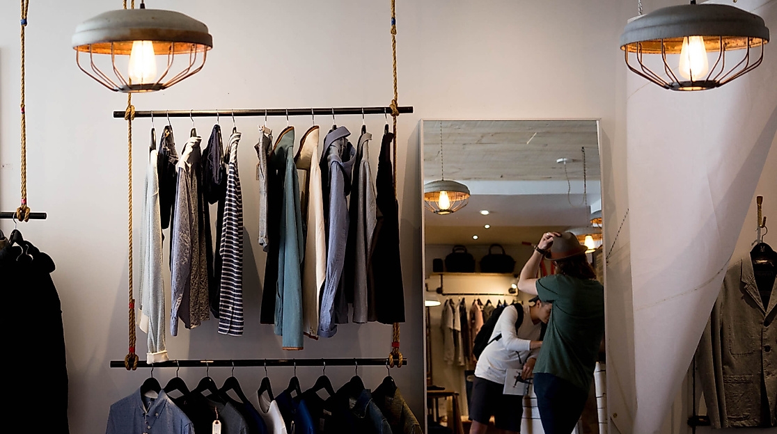 Stilvoller Second-Hand-Shop mit Hängelampen, Spiegel und ausgewählter Mode auf Kleiderstangen in Hamburg