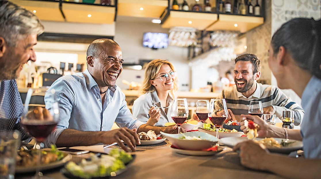 5 lachende Person beim Essen in einem Restaurant
