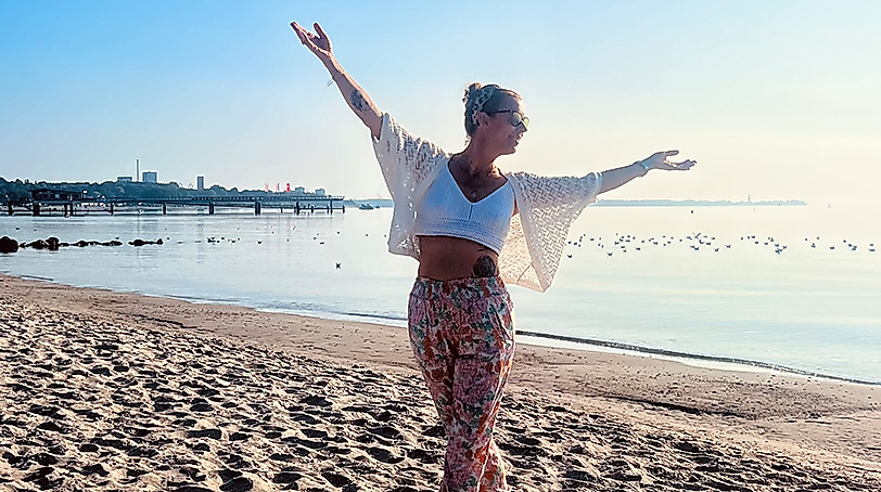 Frau beim Yoga am Strand mit offenen Armen an der Ostsee von Scharbeutz und Haffkrug