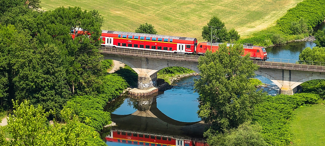 Ein Zug, der durch grüne Felder über eine Brücke fährt