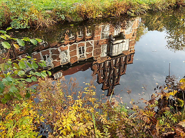 Spiegelung des Bergedorfer Schlosses im Wasser, umgeben von herbstlicher Ufervegetation in Hamburg-Bergedorf