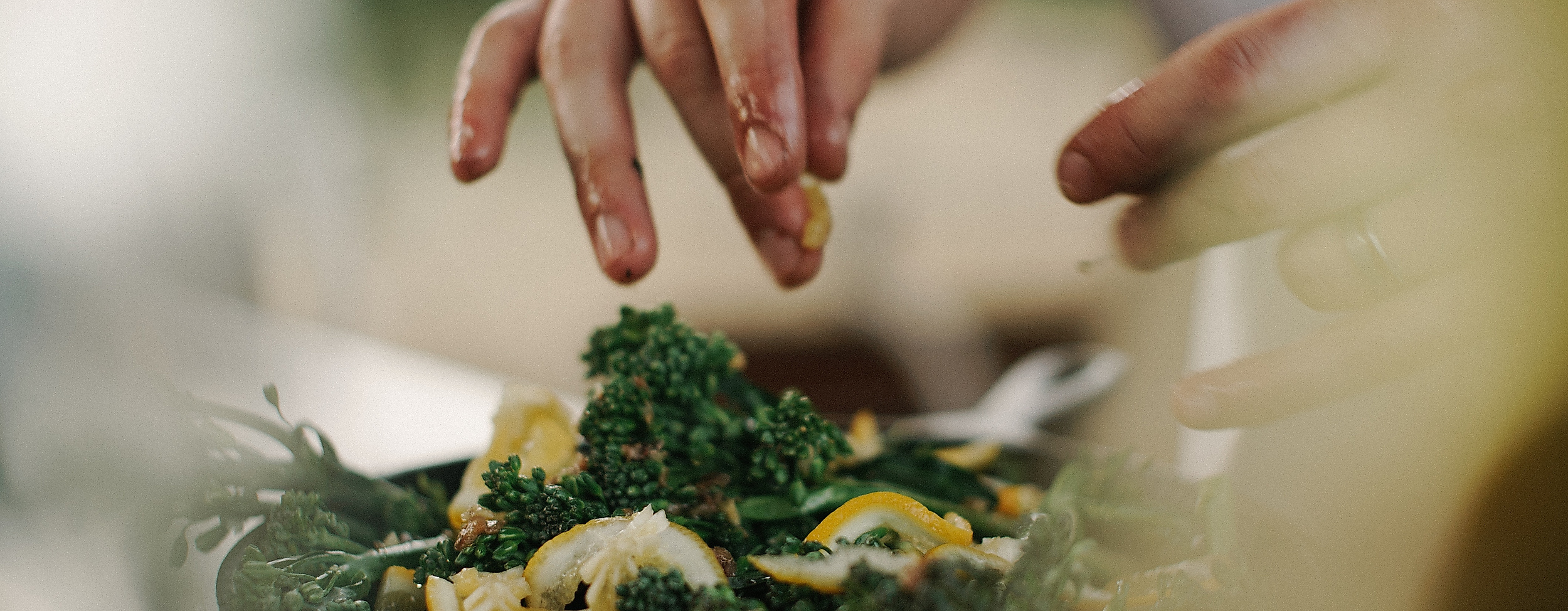 Koch verfeinert ein Gericht mit frischen Kräutern in einer Pfanne während eines Kochkurses