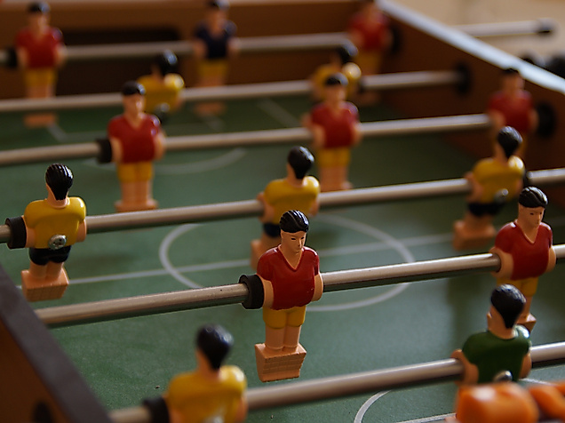 Nahaufnahme eines Tischkickers mit rot-gelben Spielfiguren auf grünem Spielfeld