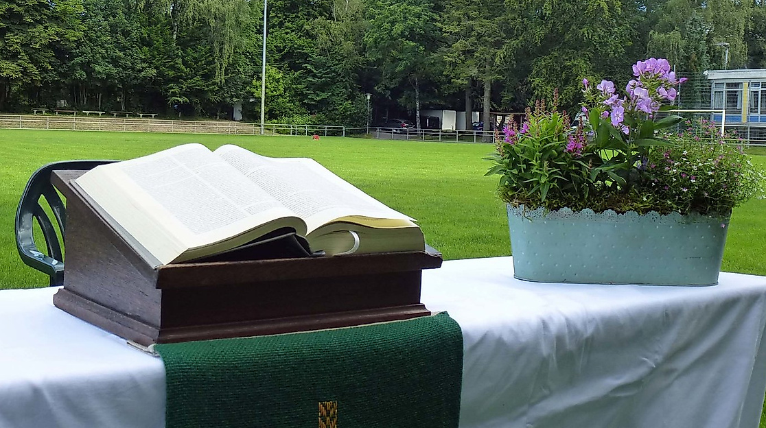 Aufgeschlagene Bibel und Blumenkorb auf einem Altar auf dem Fußballfeld