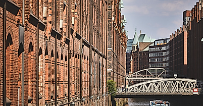 Backsteinfassaden der Hamburger Speicherstadt mit Wasserlauf und Brücke bei Tageslicht