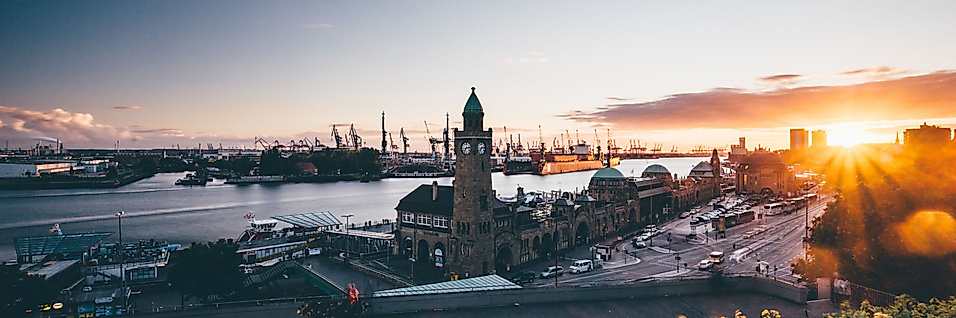 Sonnenuntergang über den Landungsbrücken mit Blick auf Uhrturm, Elbe und Hafenkräne im Hintergrund