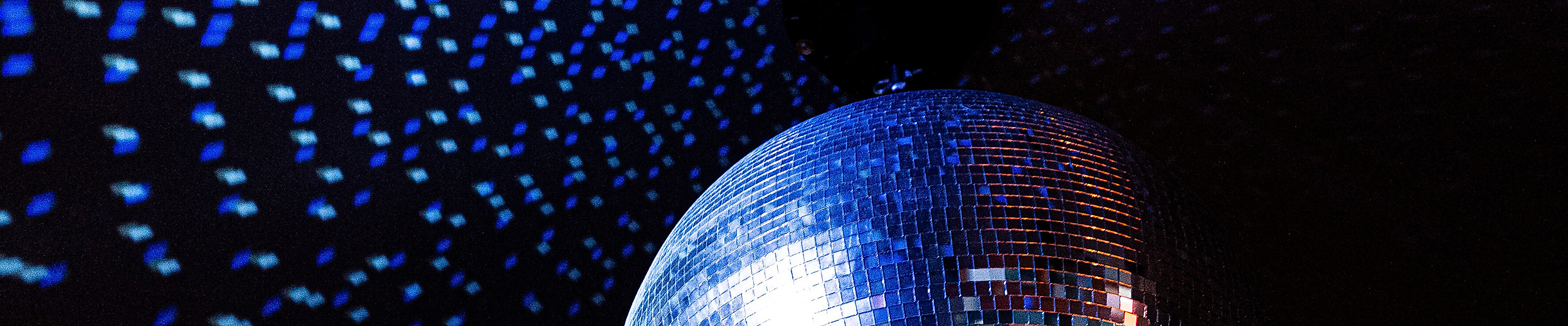 Rotierende Discokugel wirft blaue Lichtreflexe in dunklem Clubambiente