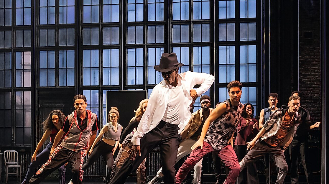 Szenenbild Michael Jackson: Michael Jackson tanzend und viele Tänzer:innen im Hintergrund. 