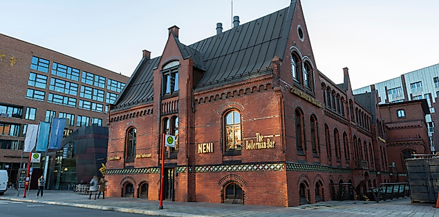 Backsteingebäude der Boilerbar in der HafenCity Hamburg mit beleuchtetem Eingang und moderner Umgebung