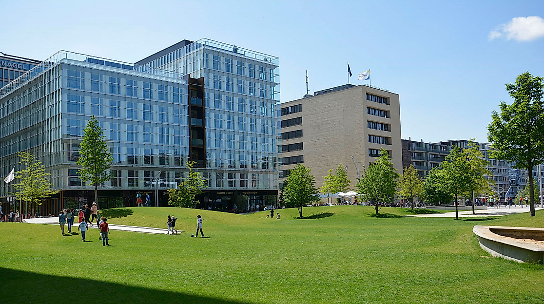 Sandtorpark in der HafenCity mit breiten Wegen, grüner Rasenfläche und moderner Architektur bei Sonnenschein.