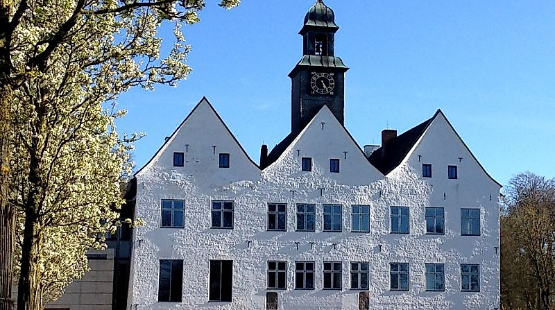 Weißes Herrenhaus unterm blauen Himmel im Sonnenschein.