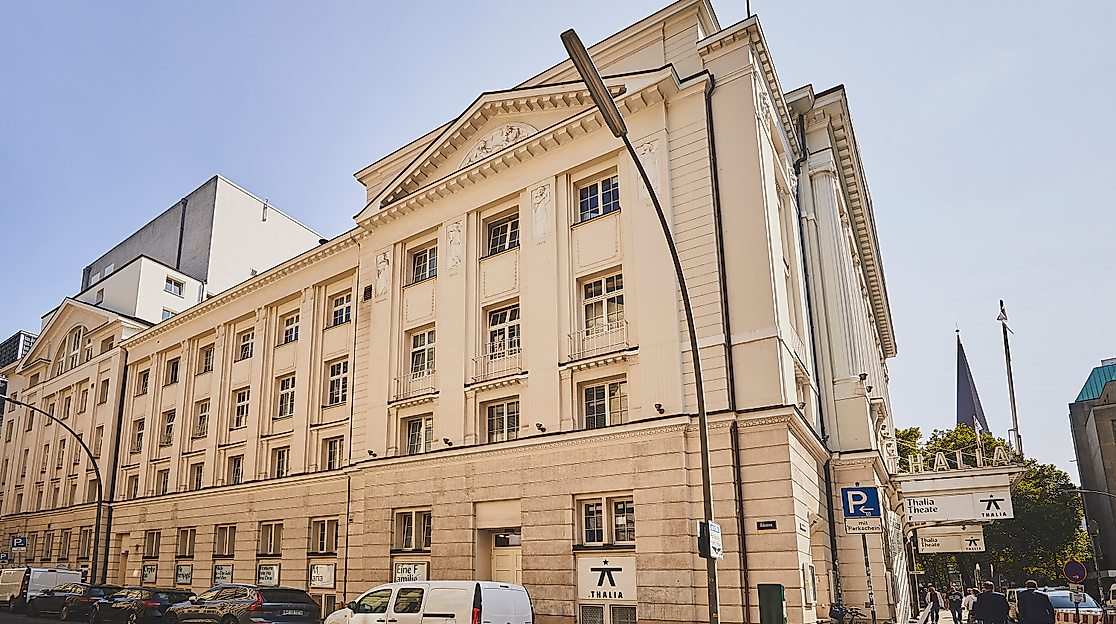 Gesamtansicht des Thalia Theaters Hamburg mit historischer Fassade an belebter Straßenecke bei Sonnenschein.