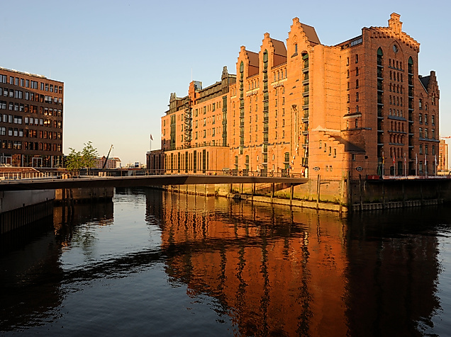 Backsteinfassade des Internationalen Maritimen Museums im Abendlicht mit Spiegelung im Wasser.