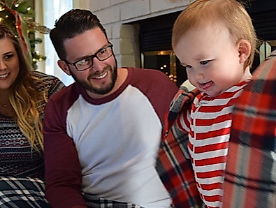 Eltern mit Kleinkind in weihnachtlich geschmückter Wohnung