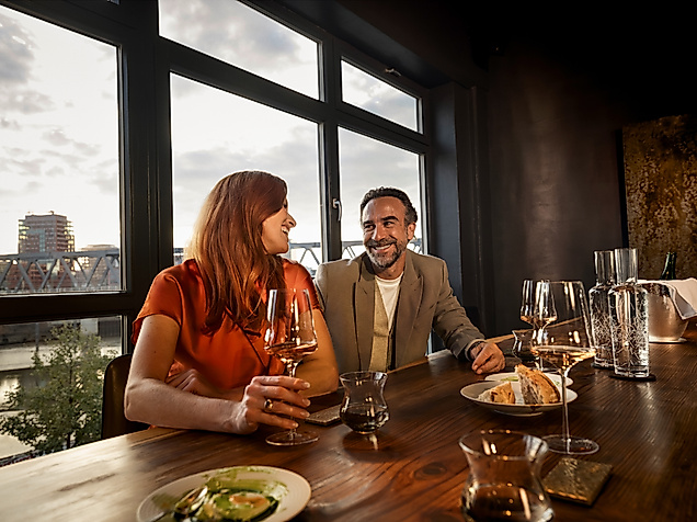A couple sits at a table in the restaurant with a glass of wine 100/200
