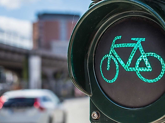 Grüne Fahrradampel vor Straßenverkehr und moderner Stadtkulisse in Hamburg.