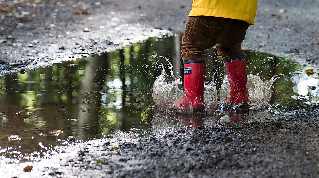 Kind mit Gummistiefeln springt in eine Pfütze – wetterfester Spaß in Hamburg bei jedem Wetter