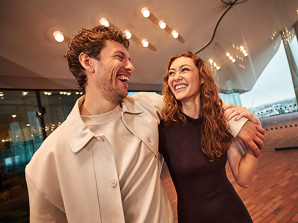 Fröhliches Paar in der Elbphilharmonie Hamburg unter warmem Licht – gemeinsames Kulturerlebnis genießen