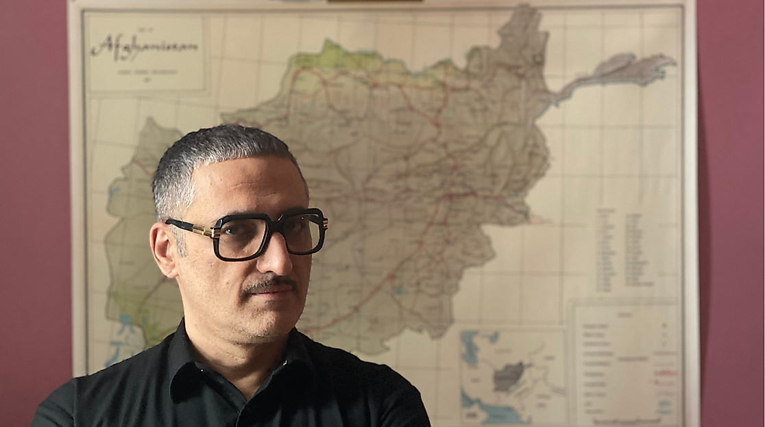 Prof. Dr. Fahim Amir steht mit ernstem Blick vor einer Landkarte