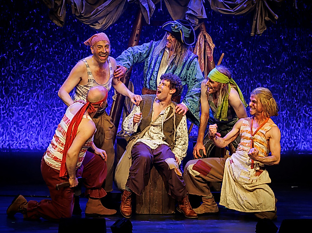 Szenenbild Der kleine Störtebeker: Störtebeker umgeben von anderen Menschen in bunten Kostümen. 