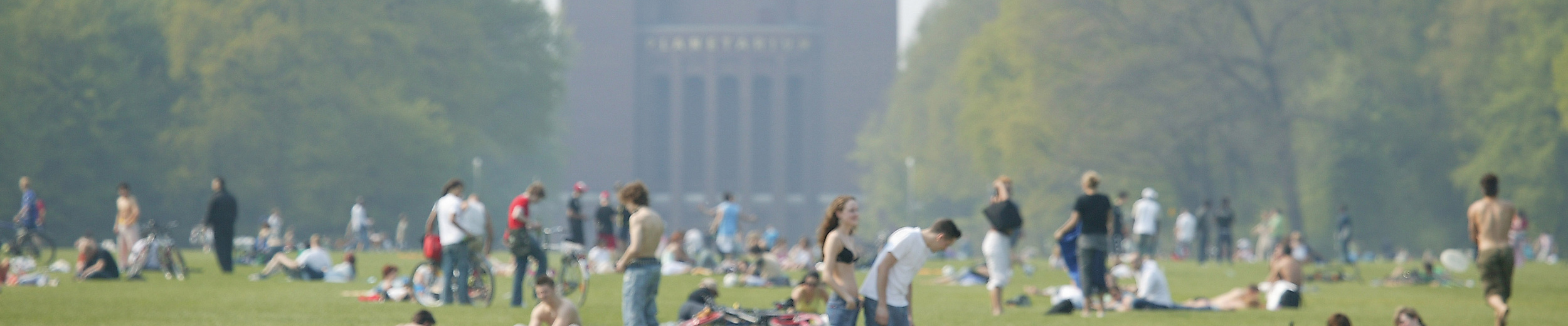 Zahlreiche Menschen entspannen auf der großen Wiese im Stadtpark mit Blick auf das Planetarium Hamburg