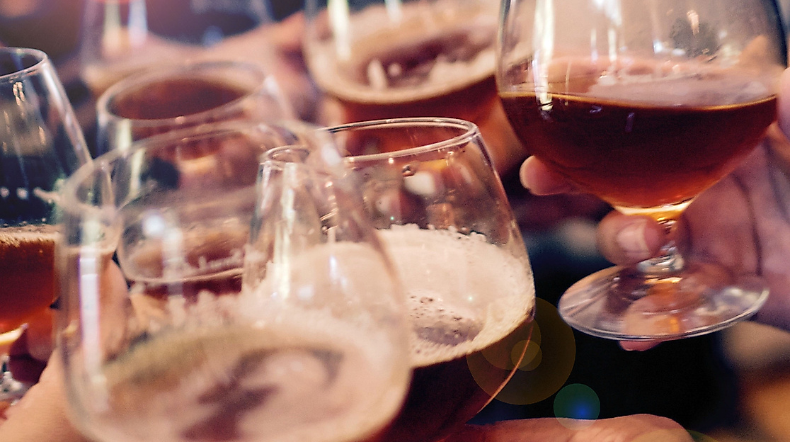 Anstoßen mit Biergläsern in geselliger Runde als Ausdruck britischer Pubkultur in Hamburg