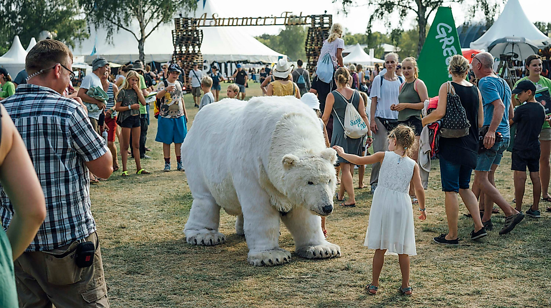 Besucher:innen auf Musikfestival mit lebensgroßer Eisbär-Puppe