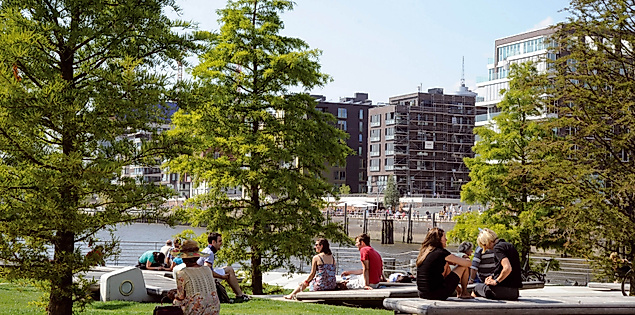 Marco-Polo-Terrassen in der HafenCity Hamburg mit Sitzinseln, Bäumen und entspannenden Menschen im Sonnenschein