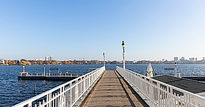 Steg an der Außenalster in Hamburg mit weitem Blick über das Wasser und die Skyline bei strahlend blauem Himmel