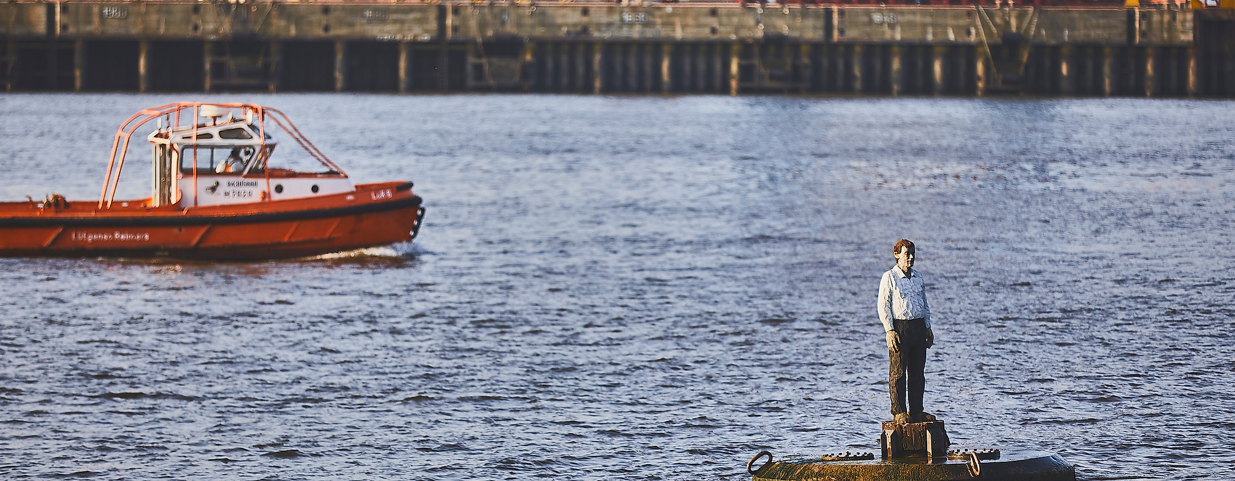 Skulptur „Die Auswanderer“ auf Boje in der Elbe vor Containerschiffen und Ausflugsboot