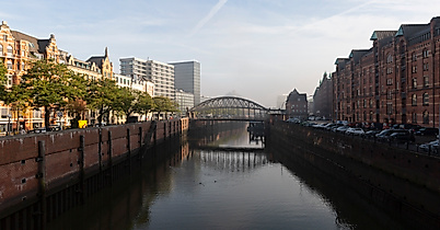 Kanal in der Hamburger Speicherstadt mit Backsteinfassaden, Brücke und Blick auf die Hafencity