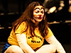 A person dressed as a clown is sitting on the stage.
