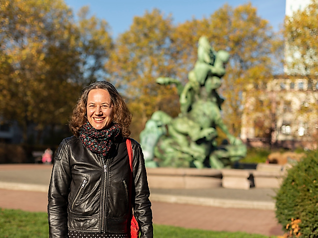 Frau im herbstlichen Park in Hamburg Altona-Ottensen vor bronzener Brunnenplastik