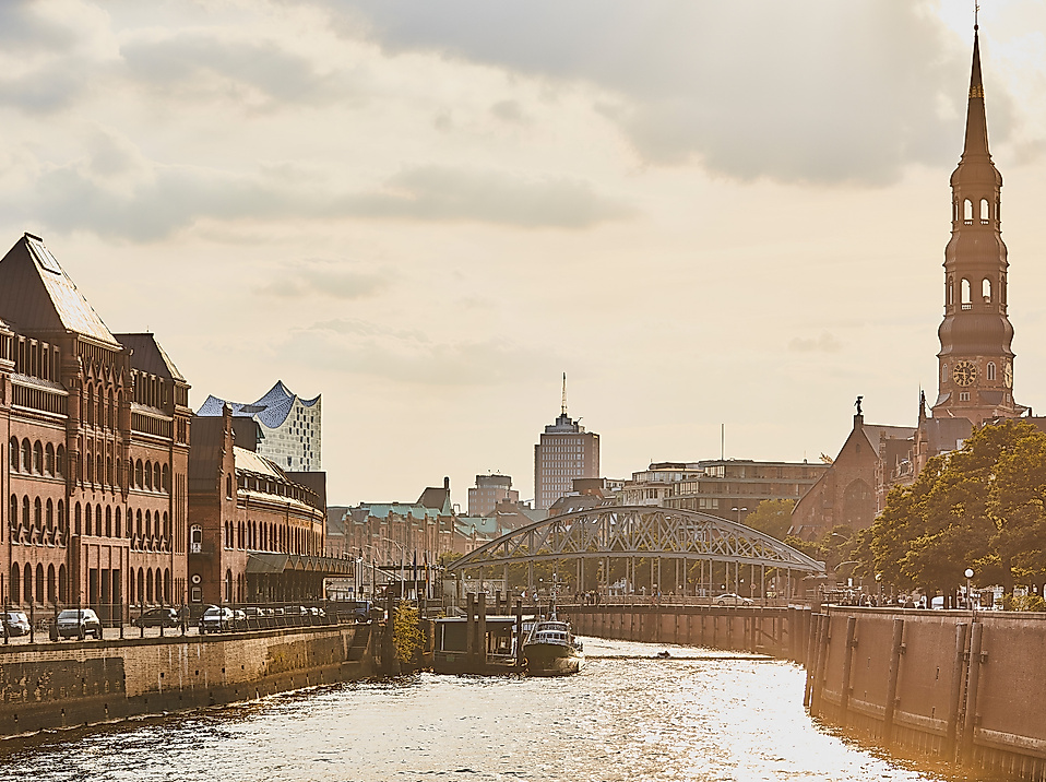 Abendstimmung in der Hamburger Speicherstadt mit Blick auf Kanal, historische Gebäude und Kirchturm