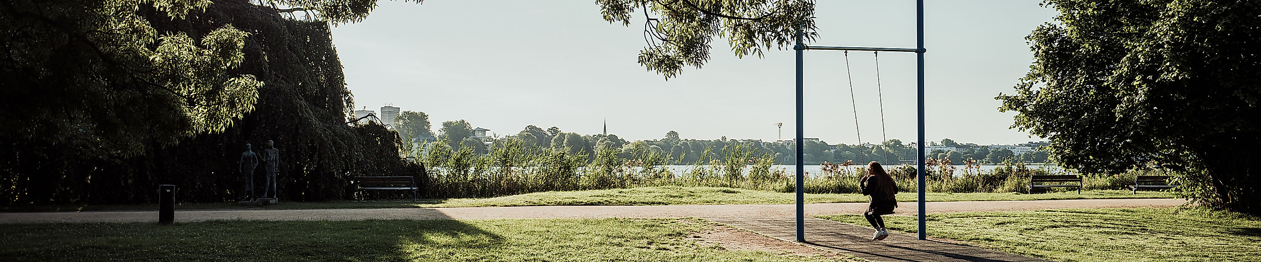 Sportbereich im Alsterpark mit Blick auf die Außenalster, umgeben von Wiese und schattenspendenden Bäumen