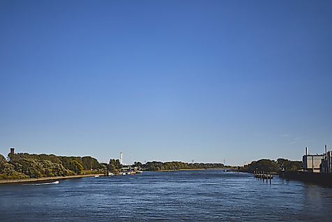 Blick über die Elbe in Hamburg bei blauem Himmel, mit Uferbebauung und Fernsehturm in der Ferne