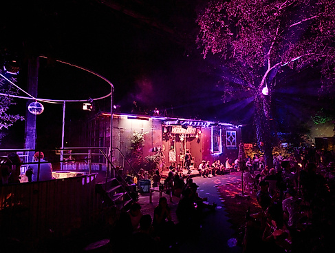 Feierliche Stimmung beim Migrantpolitan. Das Gebäude ist in pinkem Licht angeleuchtet, über dem Pool hängt eine Discokugel.
