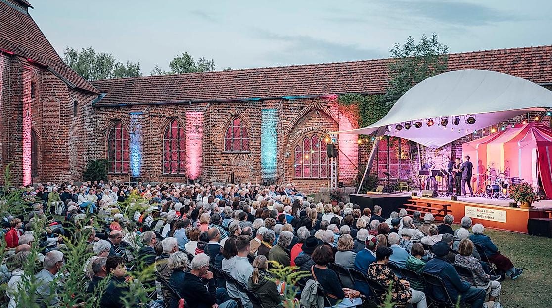 Open-Air-Konzert in beleuchteter Klosterruine, Publikum vor stimmungsvoller Festspielkulisse.