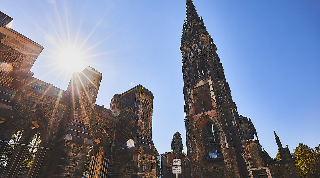 Ruine der St.-Nikolai-Kirche mit Turm als Mahnmal vor blauem Himmel und Sonnenlicht