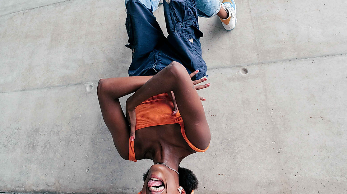 Eine junge Frau die kopfüber an einer Wand lehnt und Grimassen schneidet