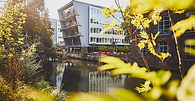 Harburger Theater am Kaufhauskanal in Hamburg, im Sonnenlicht durch Blätter mit Spiegelung im Wasser