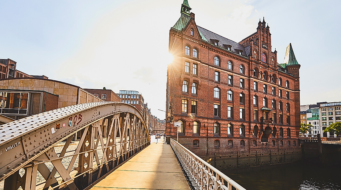 Historisches Speichergebäude am Sandtorkai im Gegenlicht der Abendsonne, Blick über eine Brücke