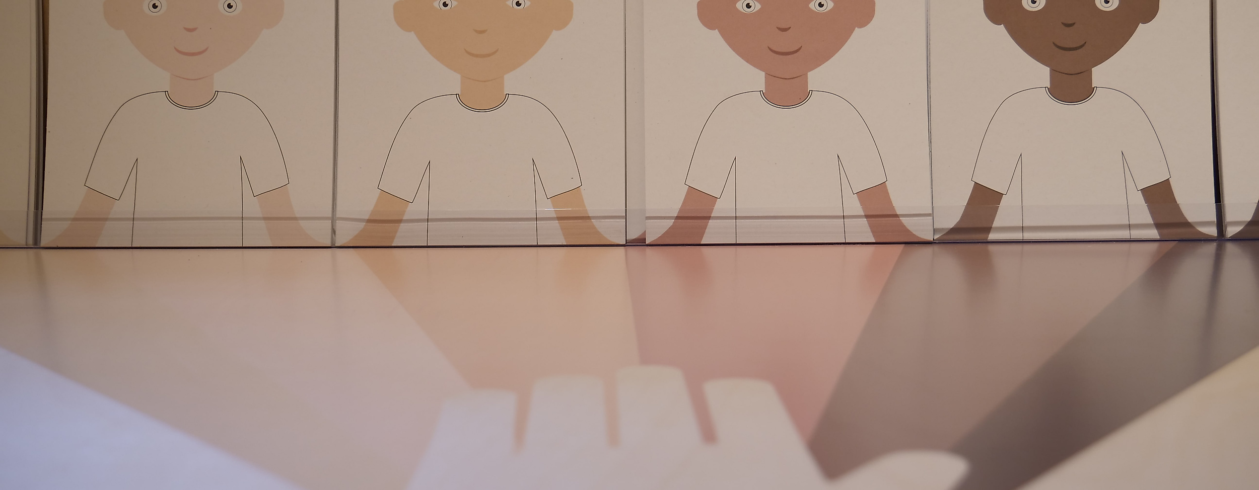 KIDS IM DIALOG - vier Kindergesichter auf Papier in verschiedenen Farbabstufungen