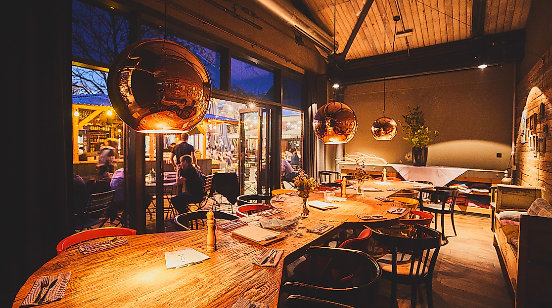 Gemütlich beleuchteter Gastraum im Alten Mädchen mit Holztischen und modern-rustikalem Design