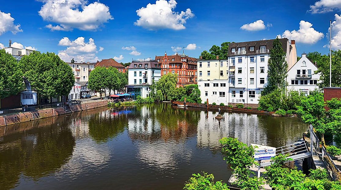 Bunte Häuserzeile am Serrahnkanal in Hamburg-Bergedorf mit Spiegelung im Wasser bei blauem Himmel