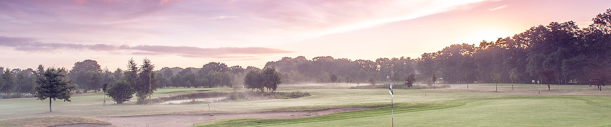 Weitläufige Golfanlage Gut Wulfsmühle bei Hamburg im Morgenlicht mit gepflegtem Fairway und Baumkulisse