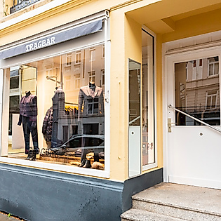 Außenansicht des Modegeschäfts Tragbar in Hamburg mit Schaufenster, Treppe und gelber Fassadenfarbe