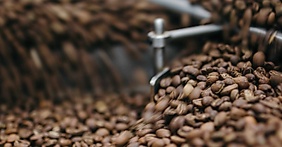 Geröstete Kaffeebohnen in einer industriellen Röstmaschine, frisch bewegt und aromatisch